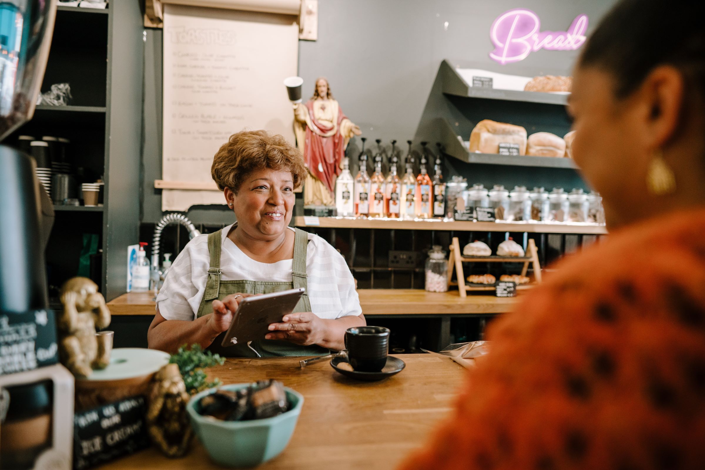 Person smiling behind a counter in a cafe serving a customer